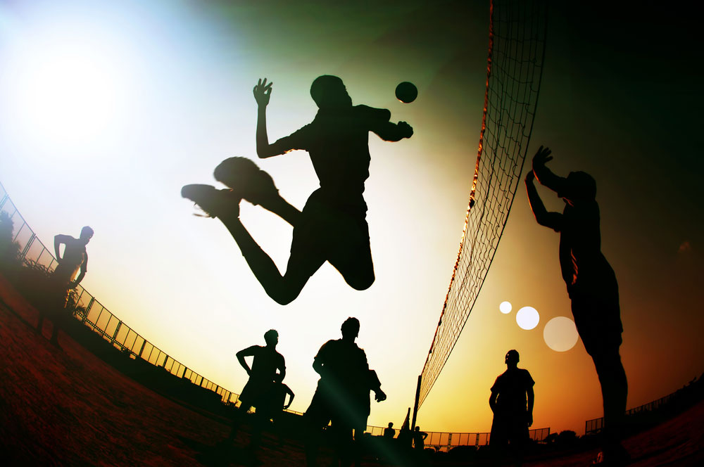 Group playing volleyball at sunset